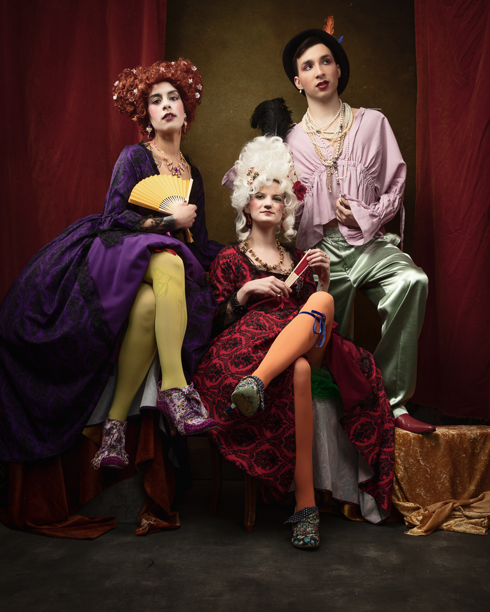 People in artistic, colourful historical costumes and wigs.