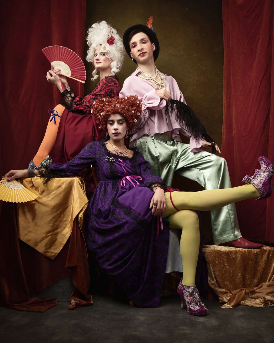 Three people in elaborate historical costumes posing dramatically.