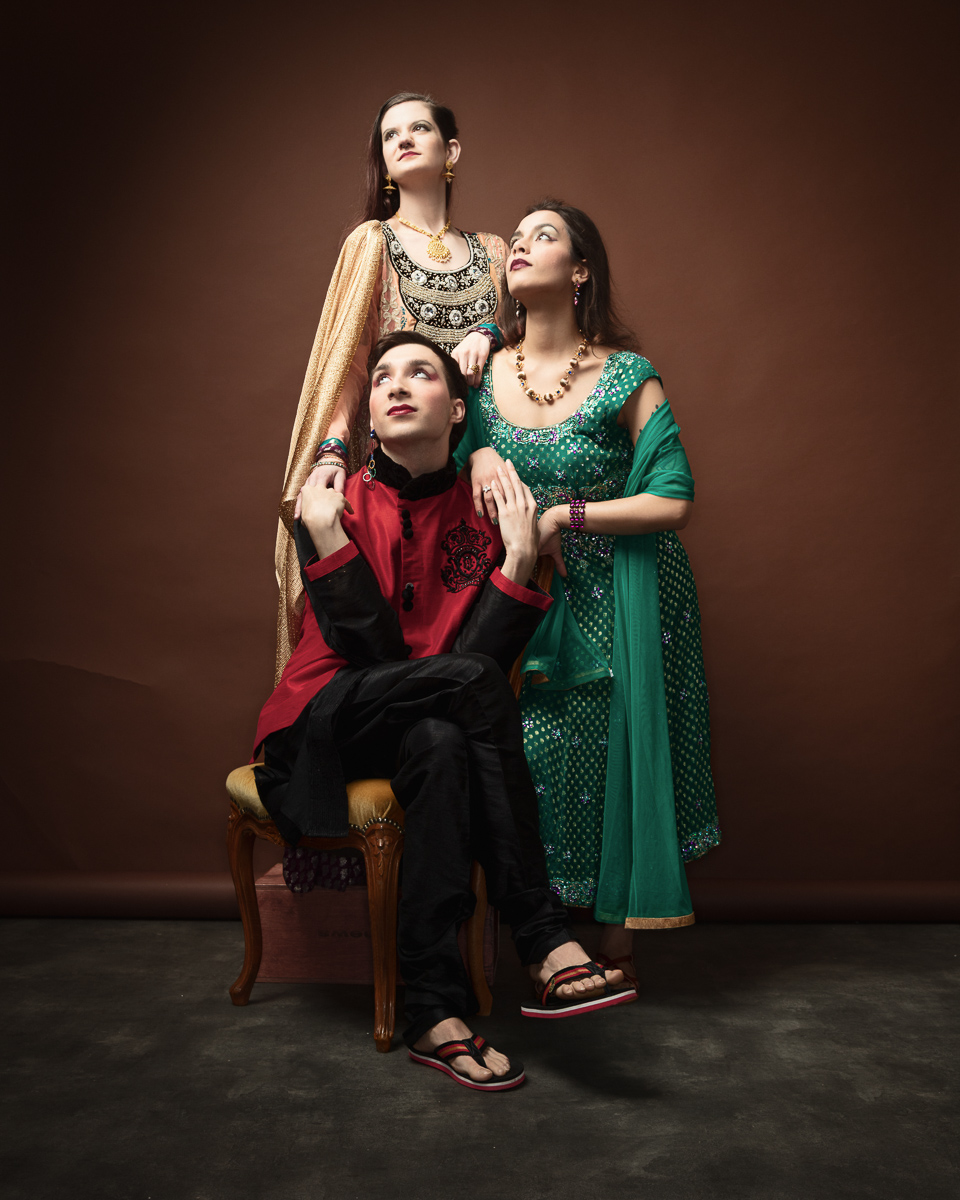Three people in colourful traditional attire posing elegantly.