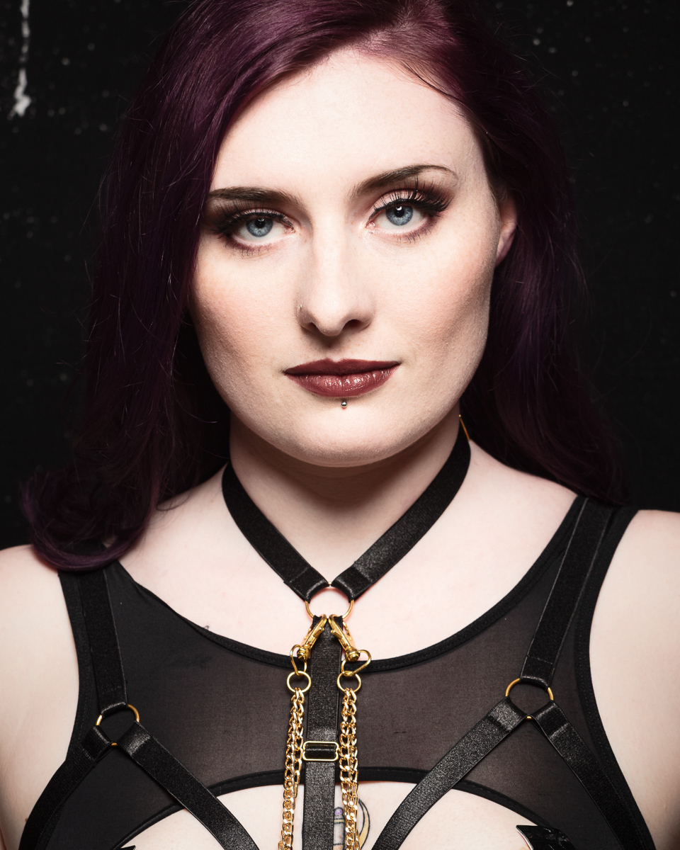 Person with purple hair, gold and black necklace.