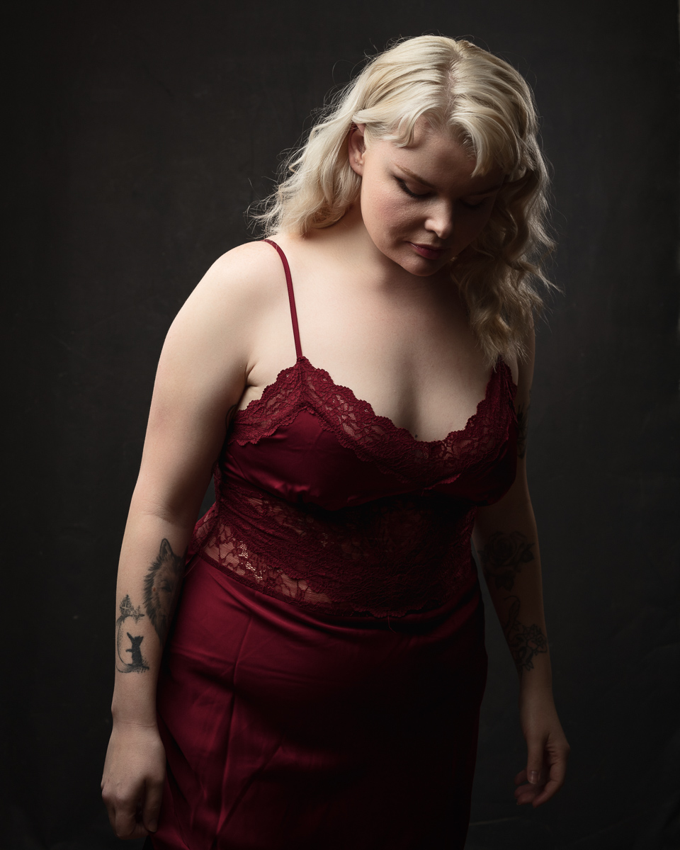Woman in red lace dress against dark background.