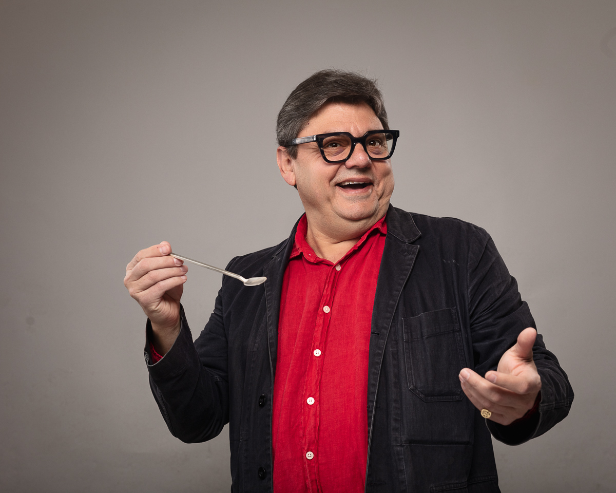 Smiling man in glasses holding a spoon.