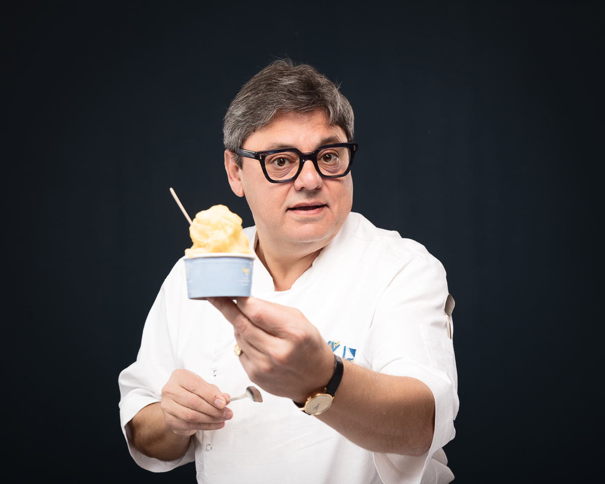 Chef in whites presenting a bowl of ice cream against a dark backdrop