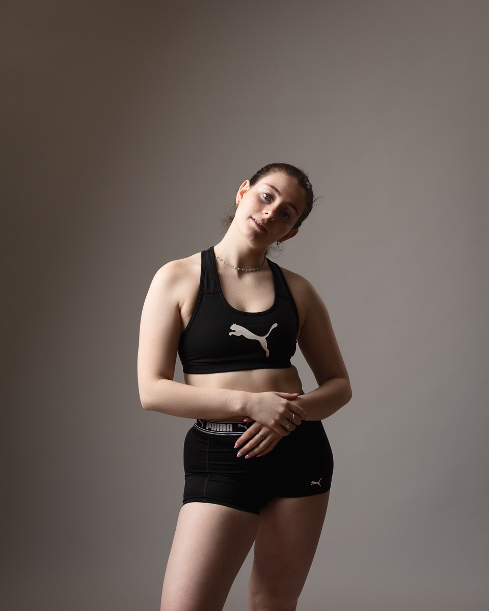 Woman modelling Puma sportswear, neutral background.