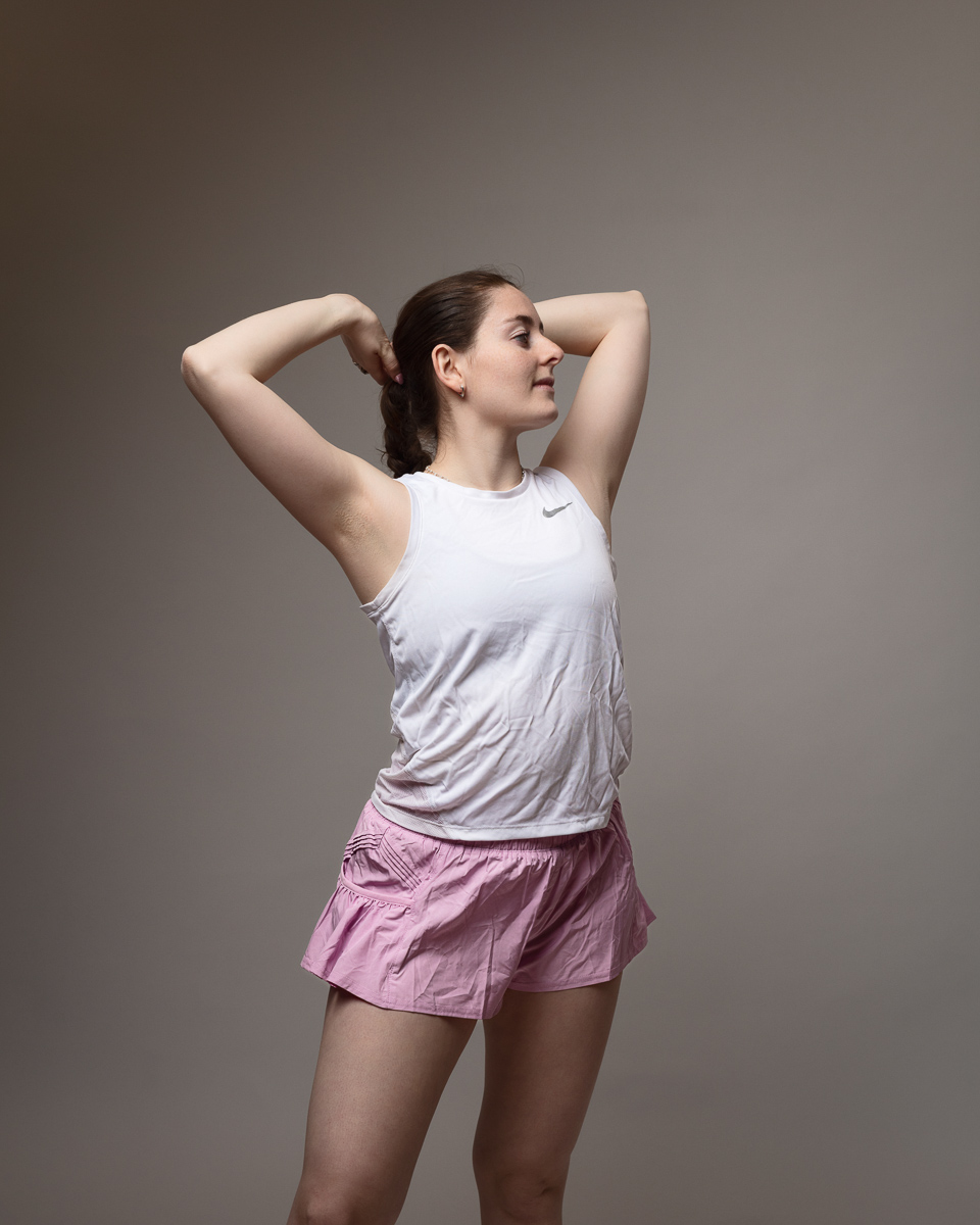 Person in exercise pose with white top, pink shorts.