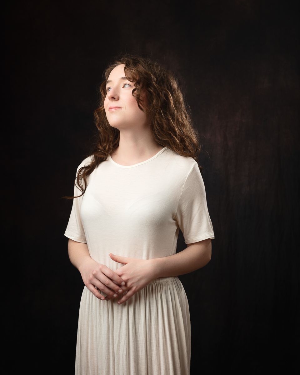 Woman in white dress looks thoughtful