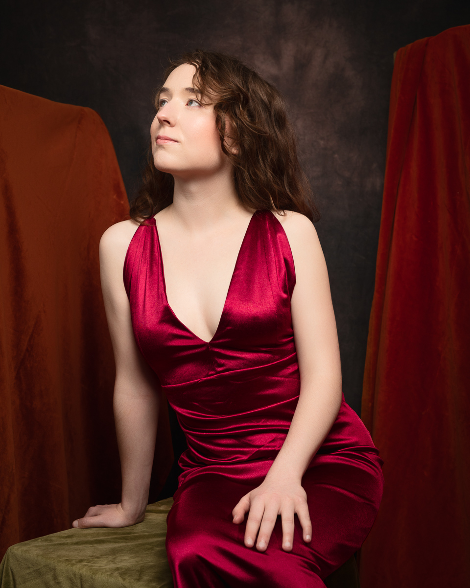 Person in red dress looking upward thoughtfully.