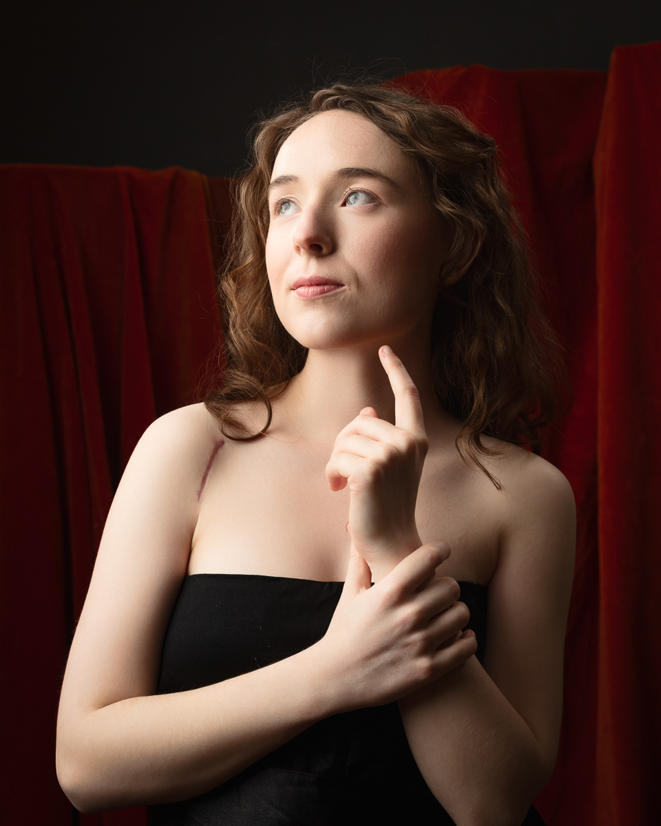 Woman in black dress posing with thoughtful expression.