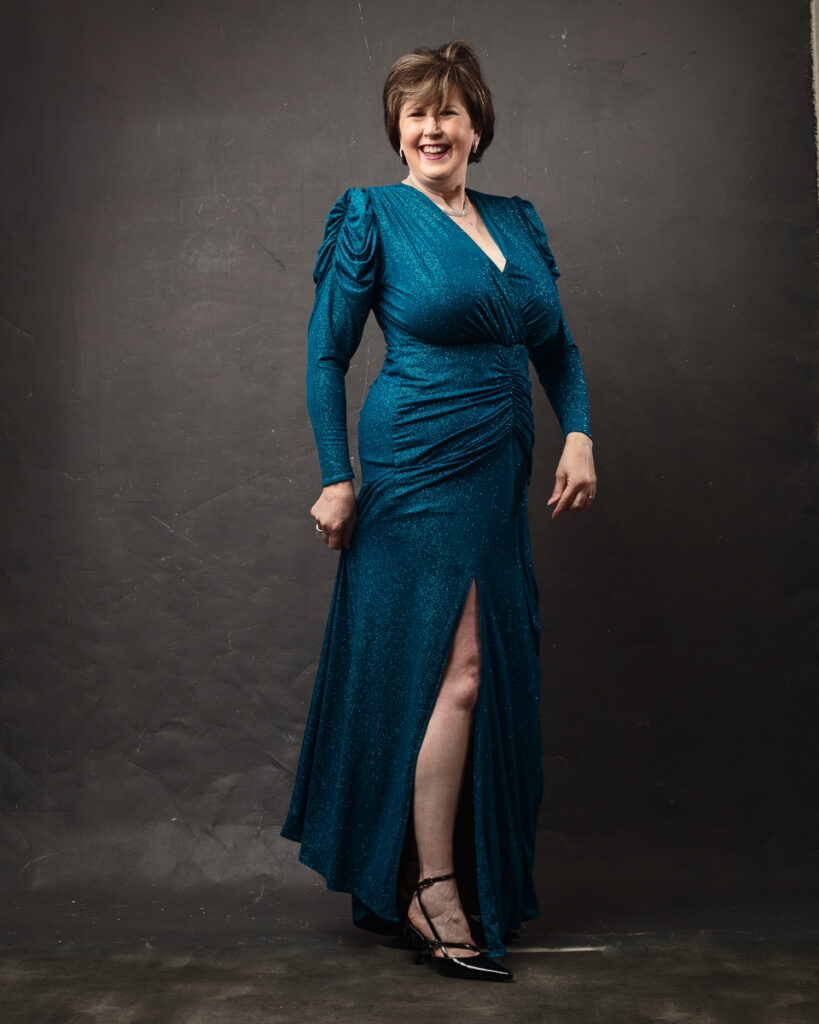 Woman in teal dress smiling confidently.