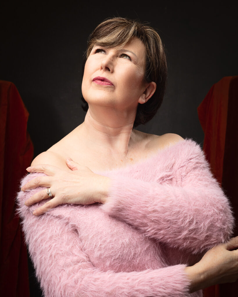 Woman in pink sweater posing thoughtfully.