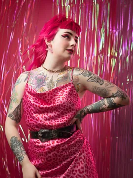 Person with tattoos in pink leopard print dress.