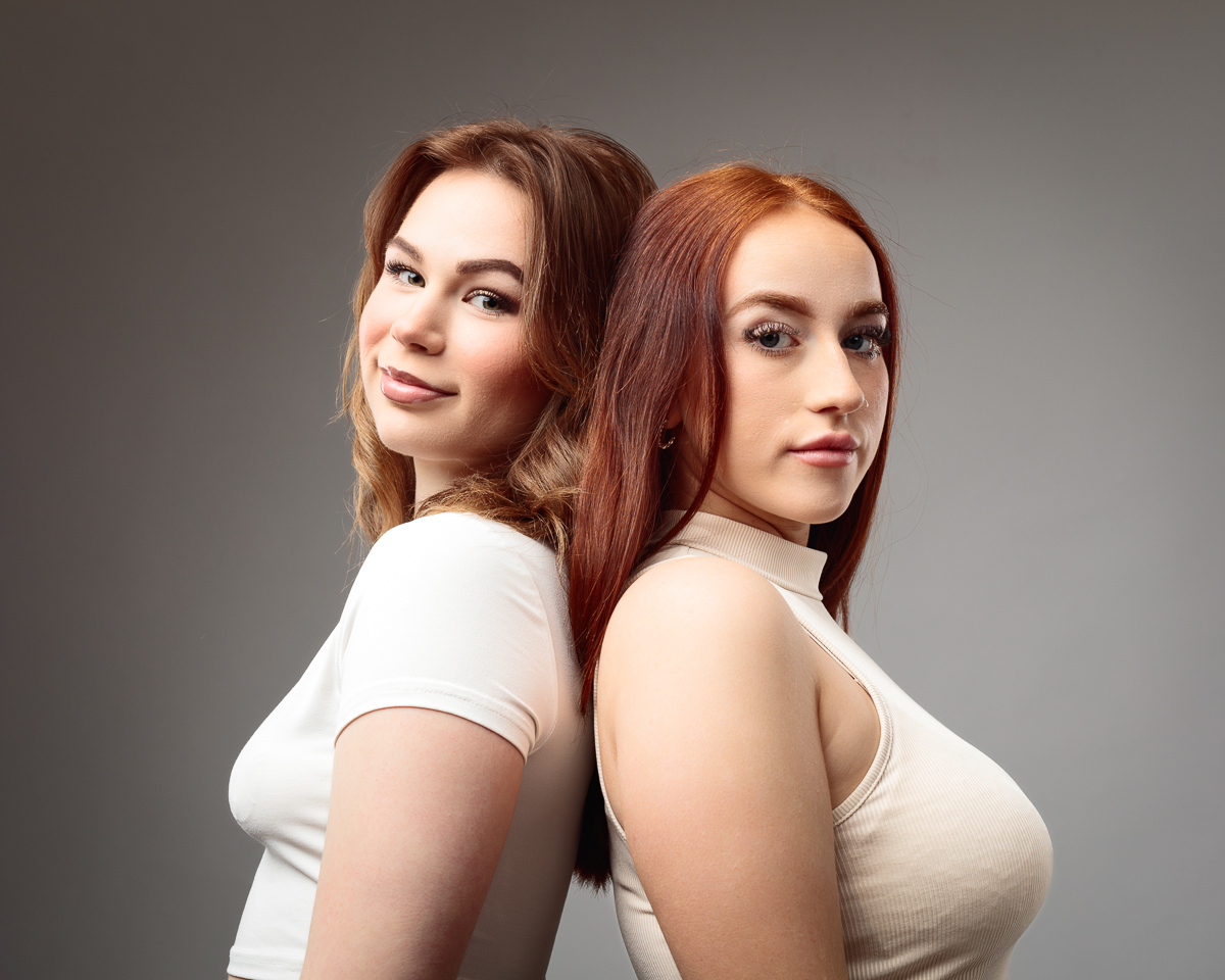 Two women back-to-back, smiling, studio portrait