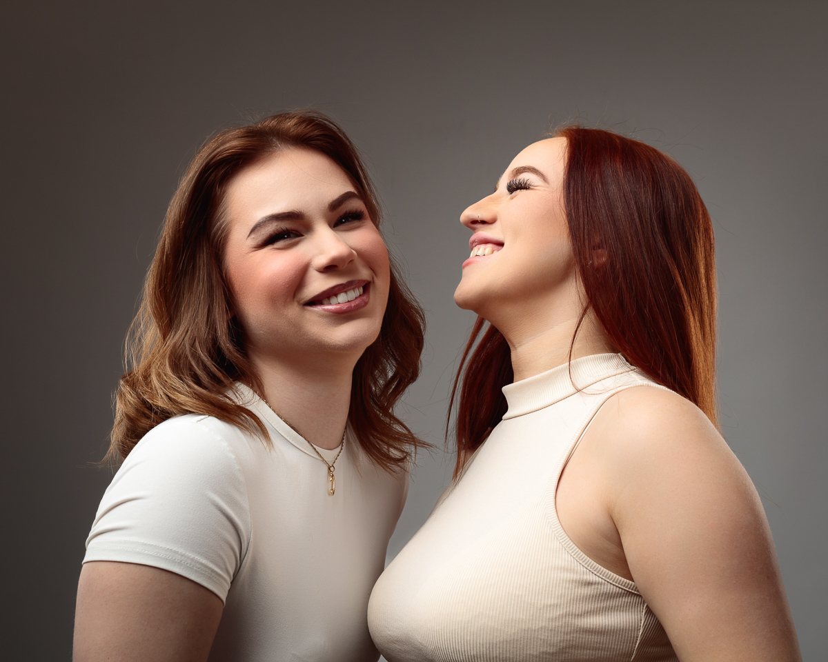 Two women smiling in studio portrait.