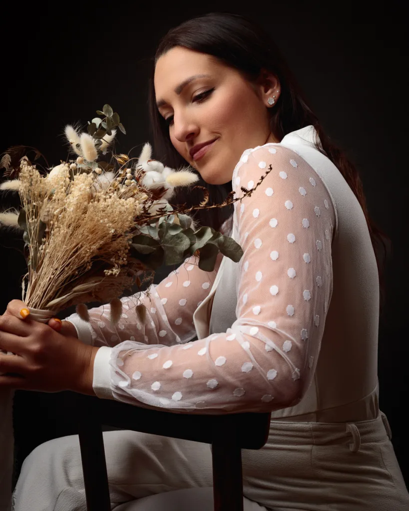 Woman in white holding dried flower bouquet.