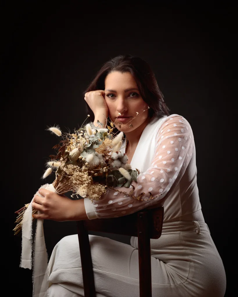 Woman holding dried flower bouquet, wearing white outfit.
