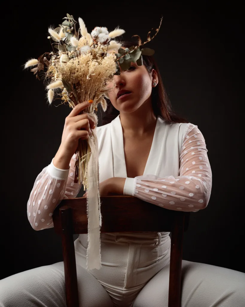 Woman in white holding dried flower bouquet.