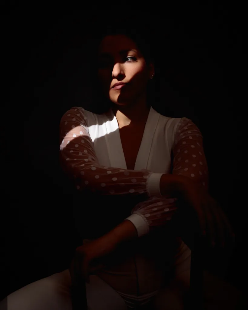 Person in dramatic lighting wearing polka-dot sleeves.