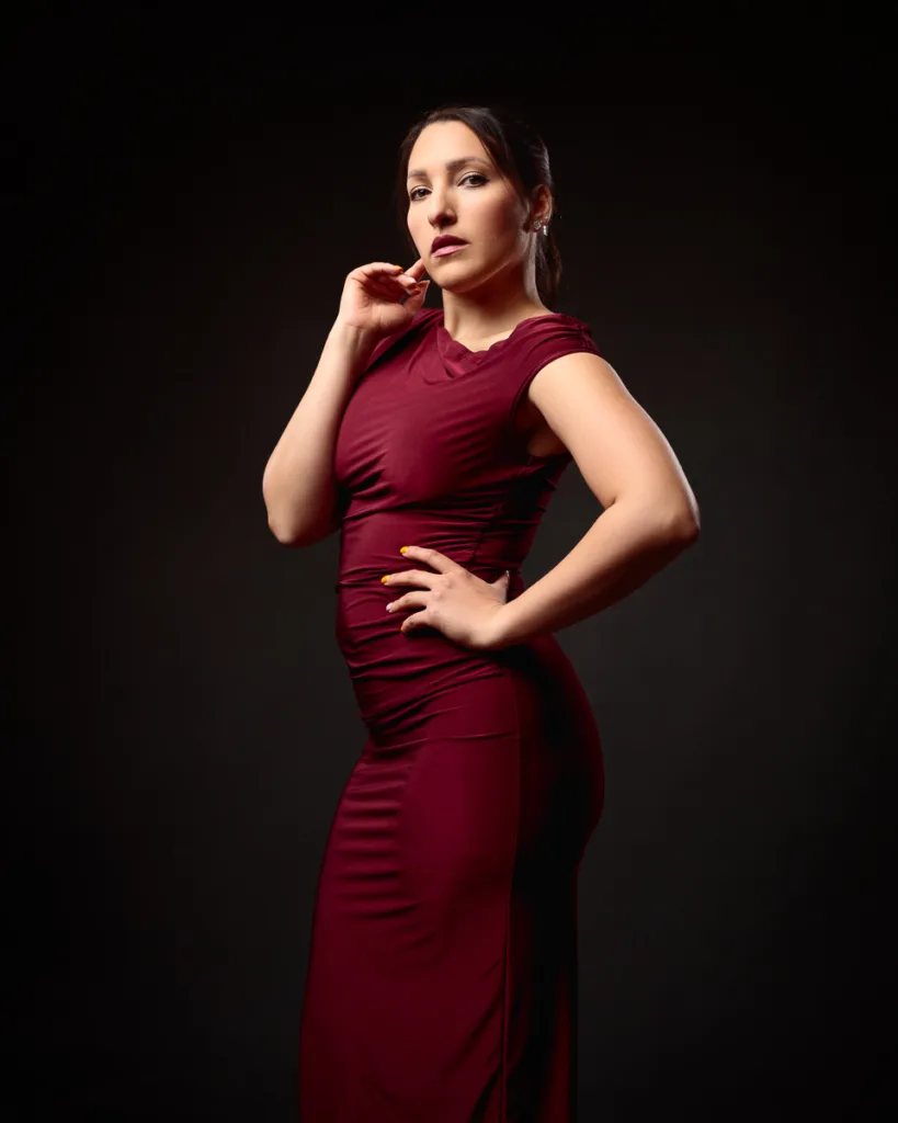 Woman in elegant red dress posing confidently.