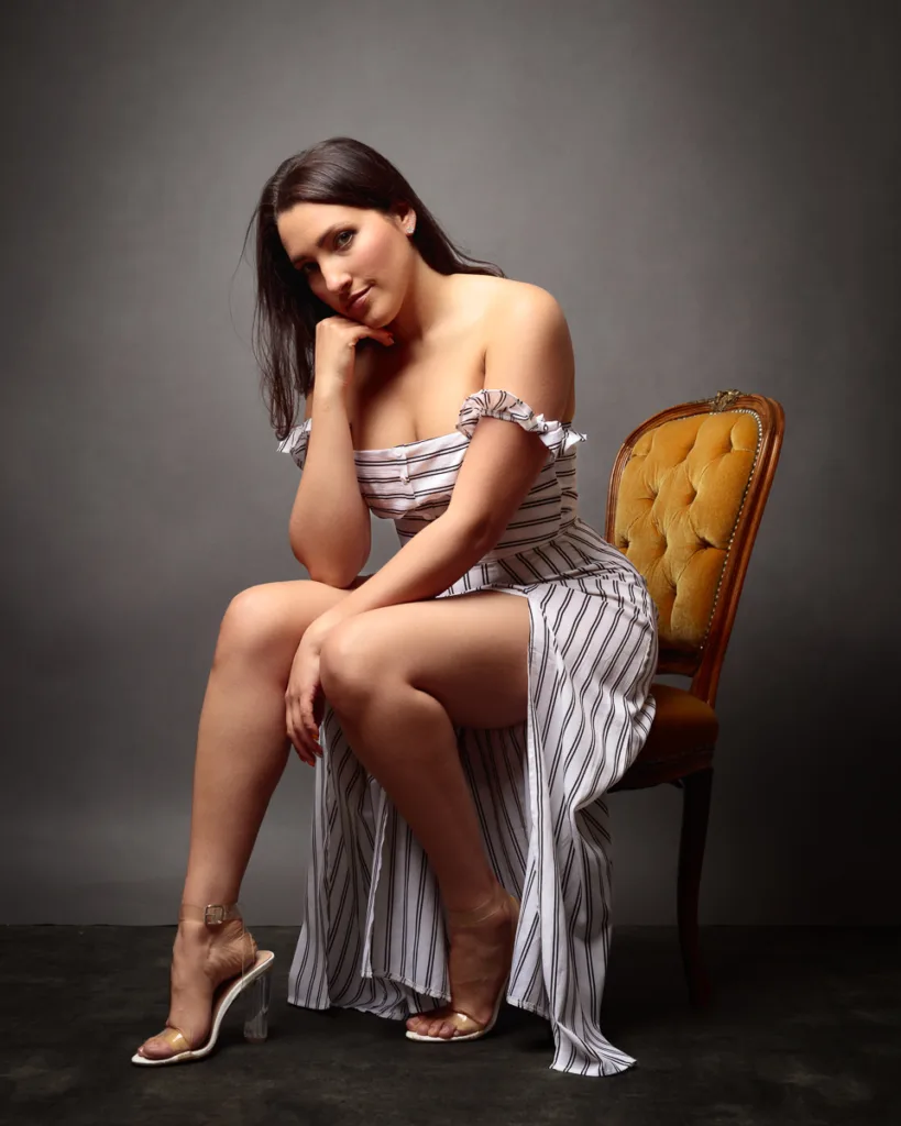 Woman seated on chair in striped dress.