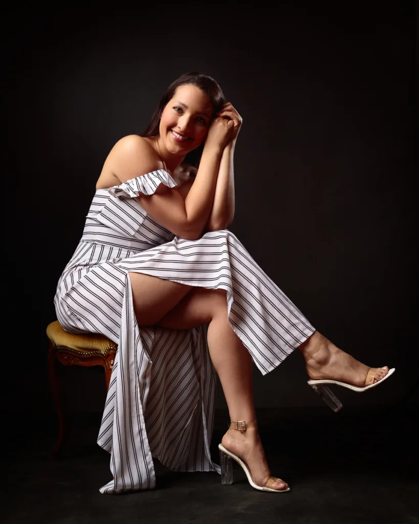 Woman in striped dress poses sitting.