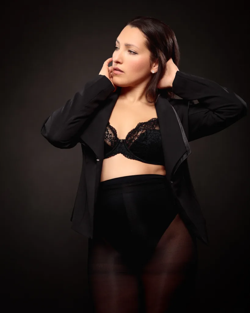 Woman in black outfit posing confidently.