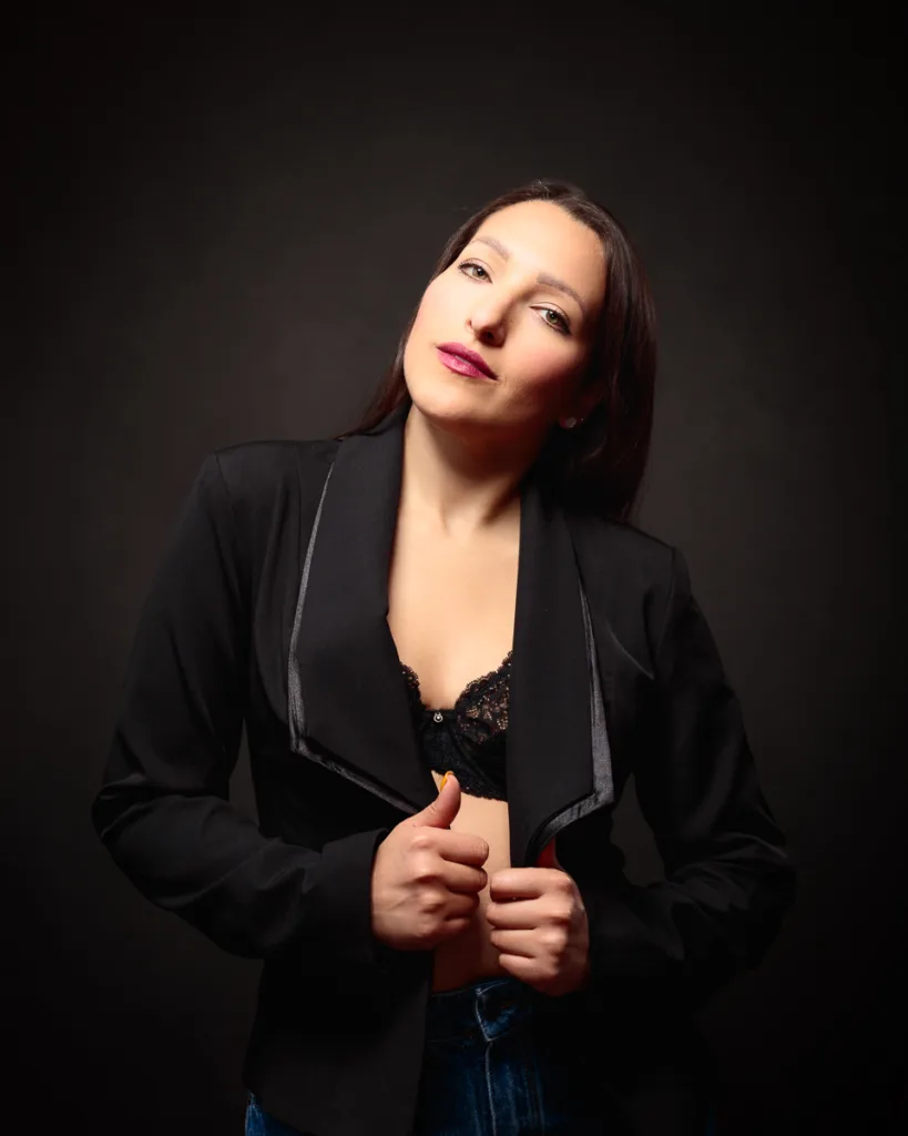 Person in black jacket and lace bra posing.