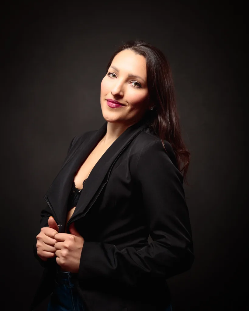 Woman in black blazer with confident smile.