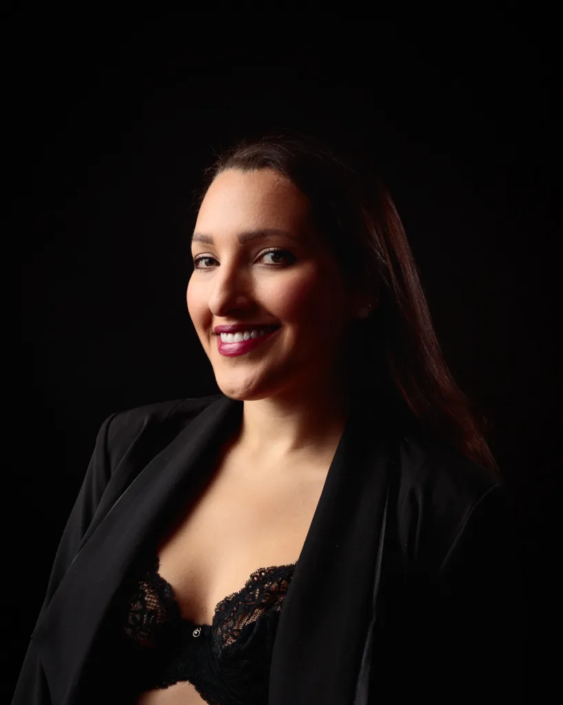 Smiling woman in black lace outfit and jacket.