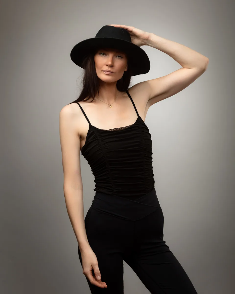 Woman in black outfit wearing a wide-brimmed hat.