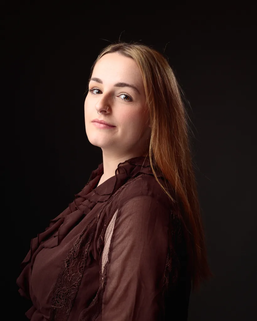 Woman with long hair in a brown shirt.