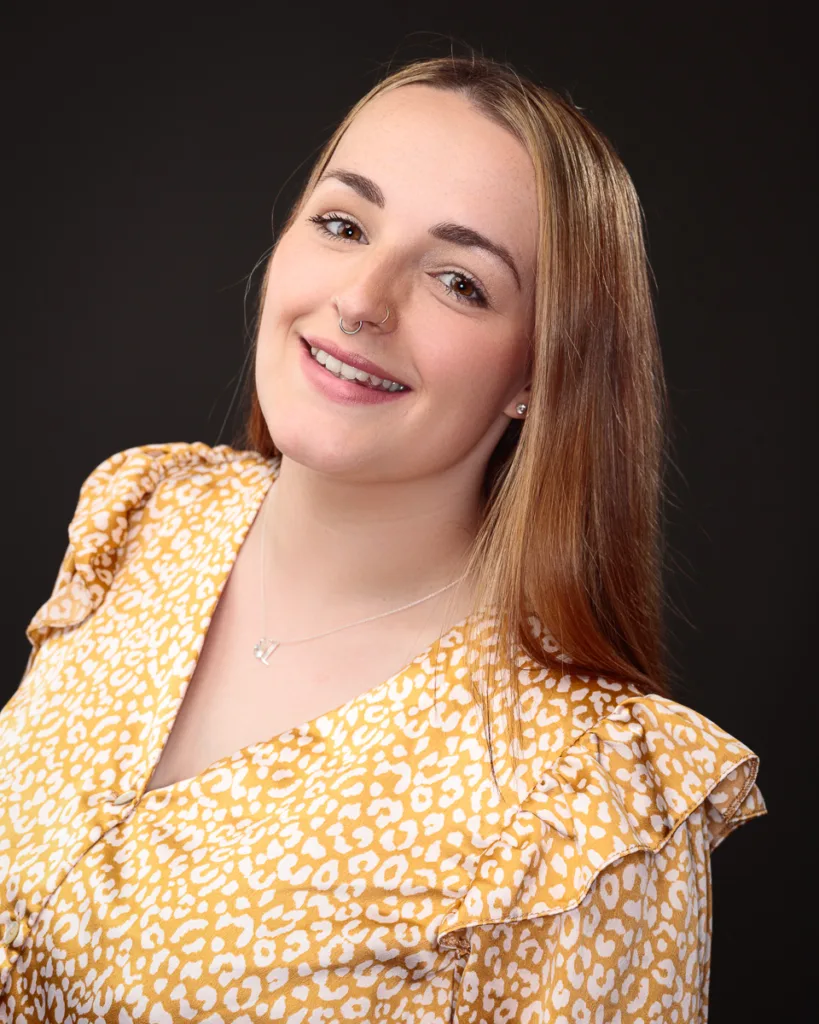 Smiling person in yellow patterned blouse.