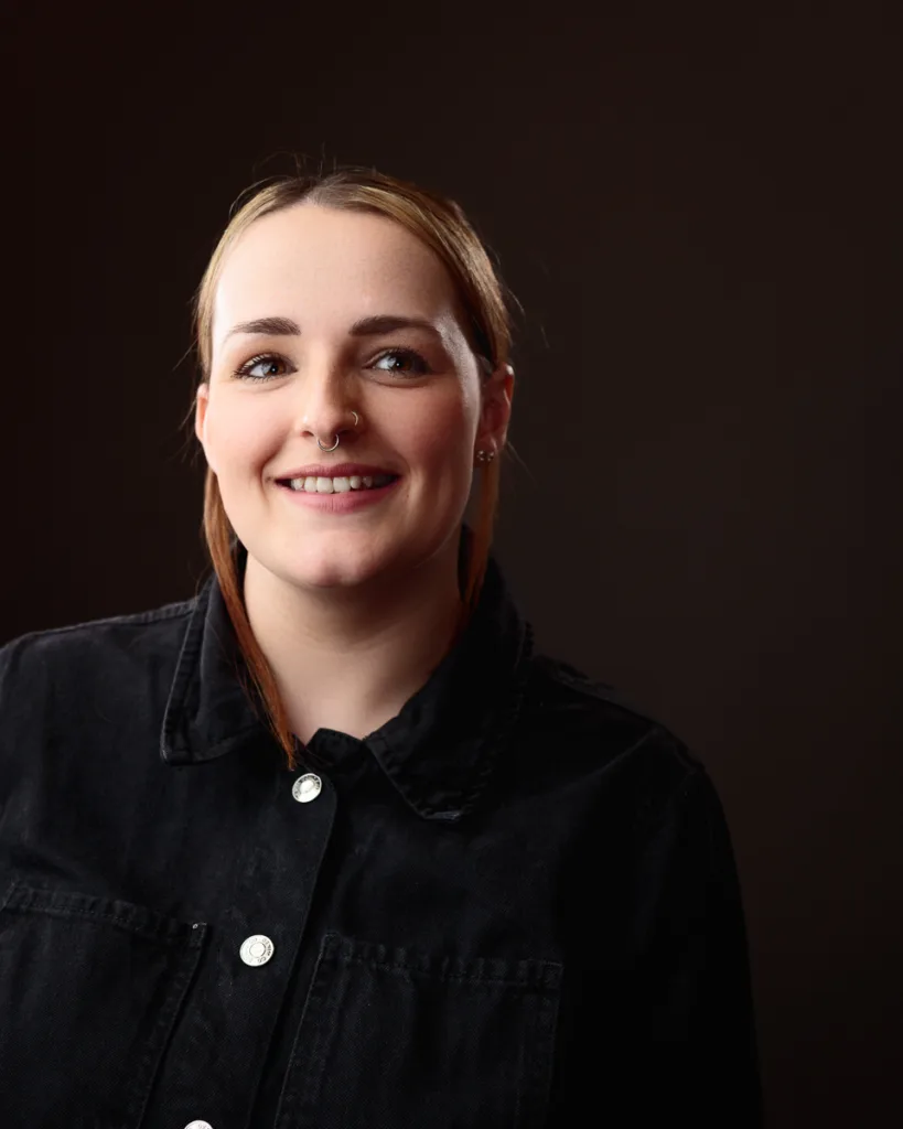 Smiling person with nose ring and black shirt.