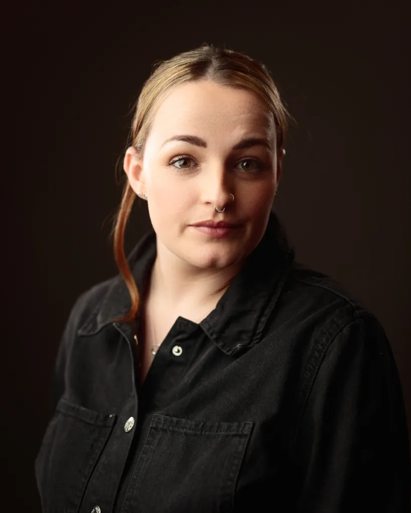 Person wearing black jacket on dark background.