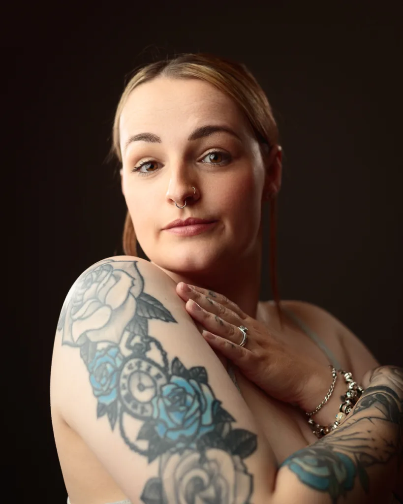 Person with floral tattoo on arm, wearing jewellery.