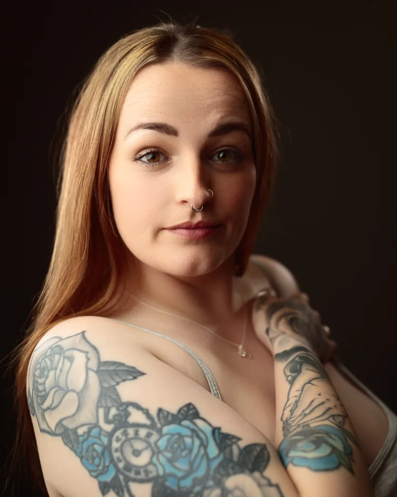 Woman with colourful floral tattoos on arm, nose ring.