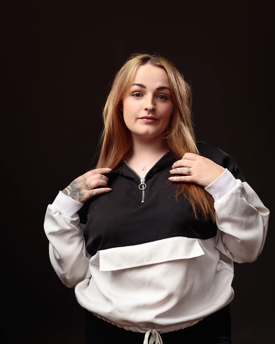 Person in black and white sweatshirt posing confidently.