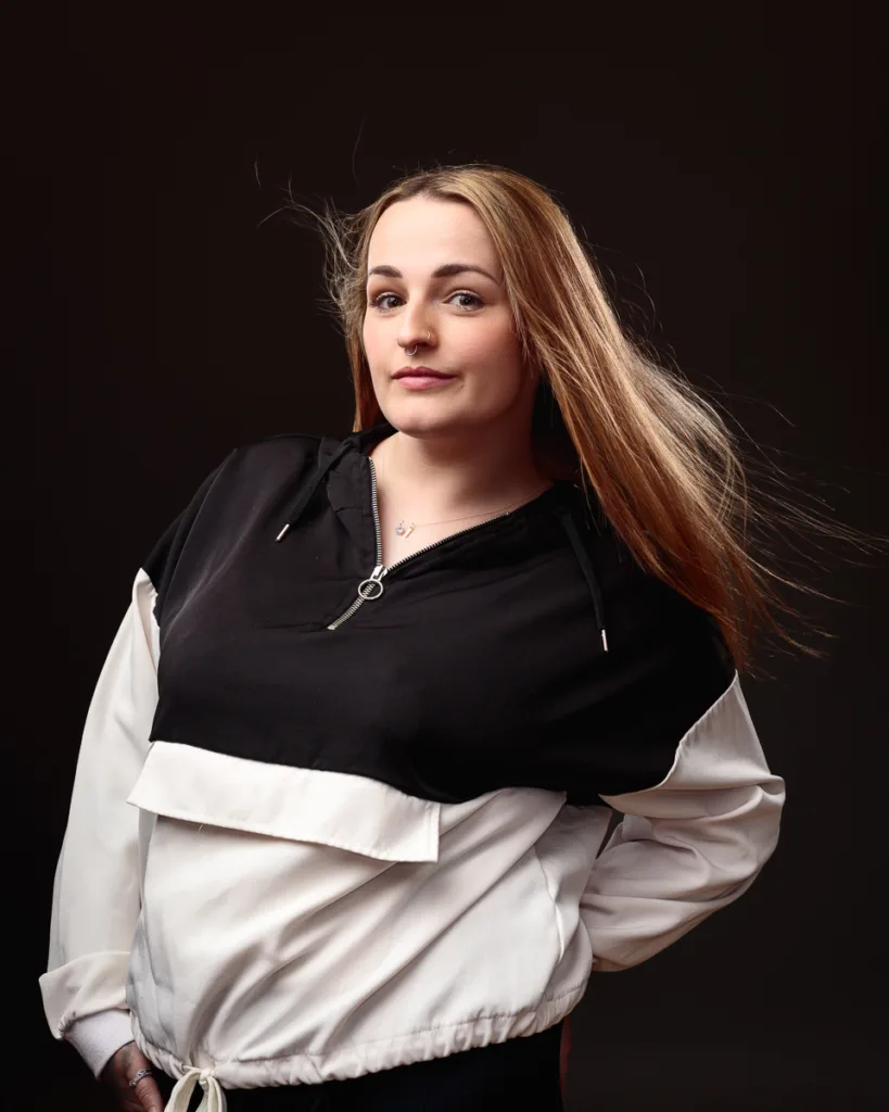 Person in black and white jacket, windblown hair