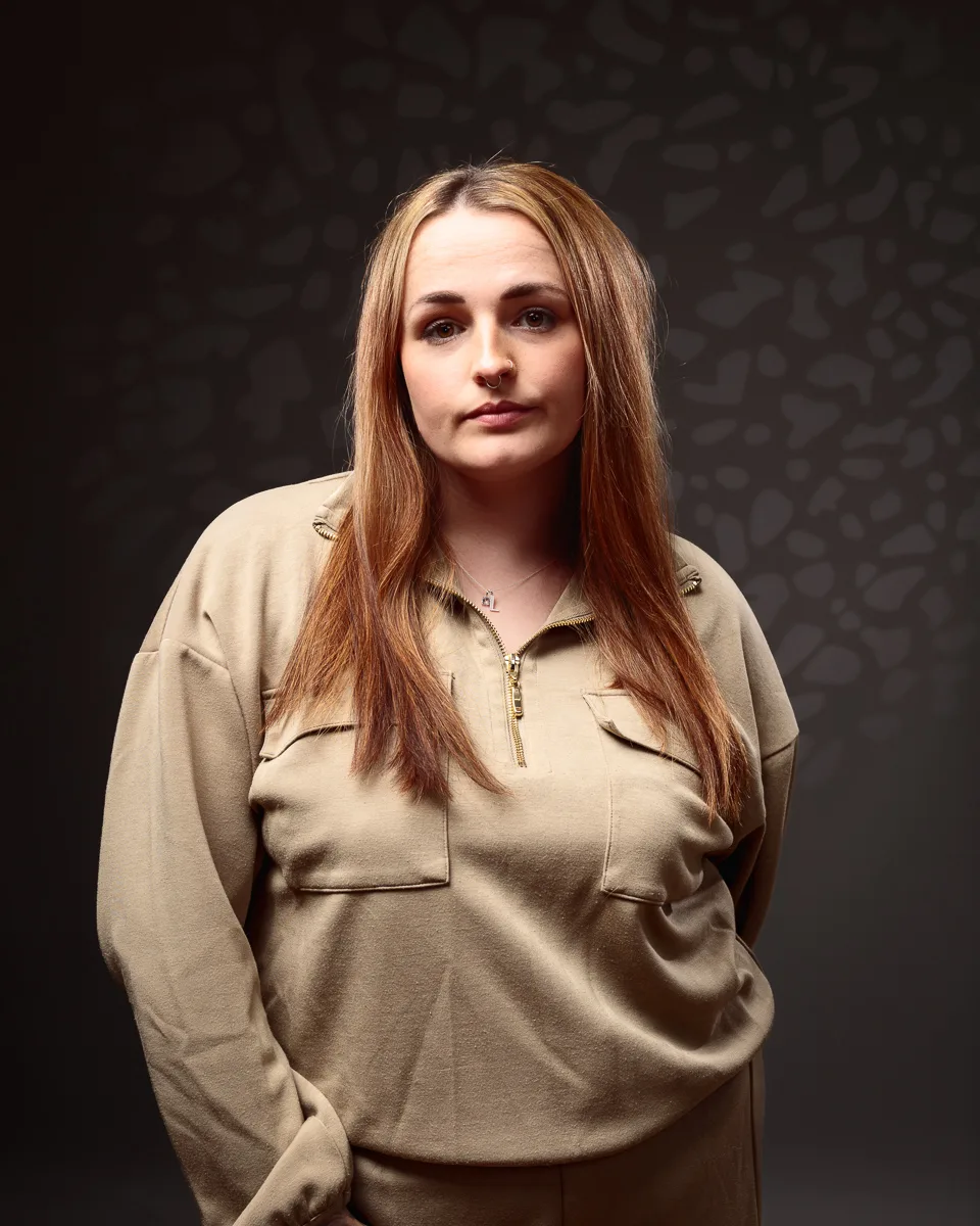 Person wearing beige outfit with patterned background.