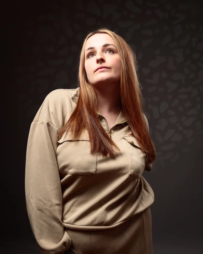 Person in brown outfit with long hair, thoughtful expression.