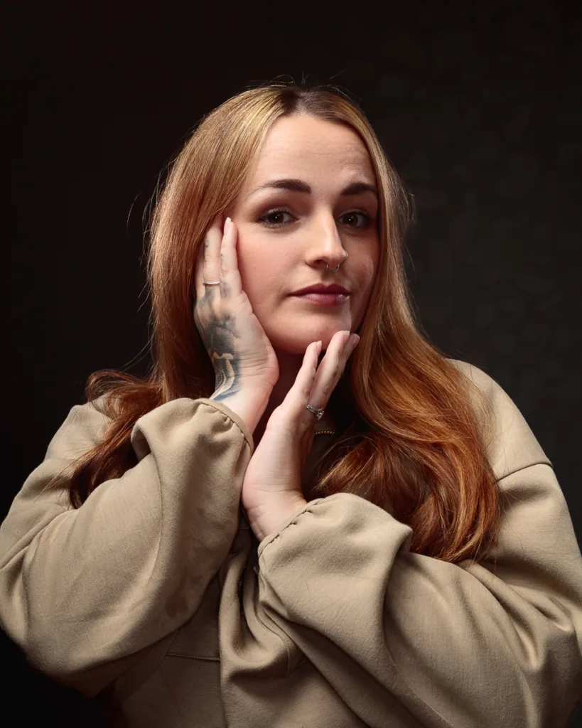 Woman posing with hands on face, smiling.