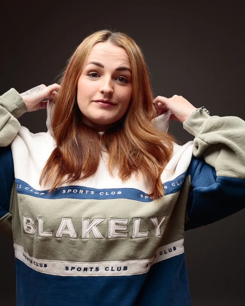 Person wearing Blakely sports club hoodie, posing confidently.