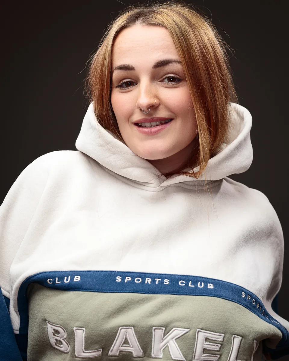 Person smiling in a branded sports club hoodie.