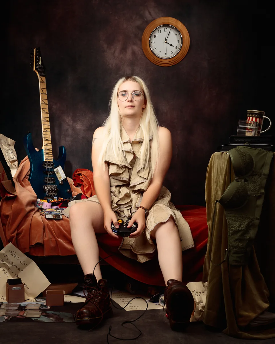 Woman playing video games surrounded by cluttered items.