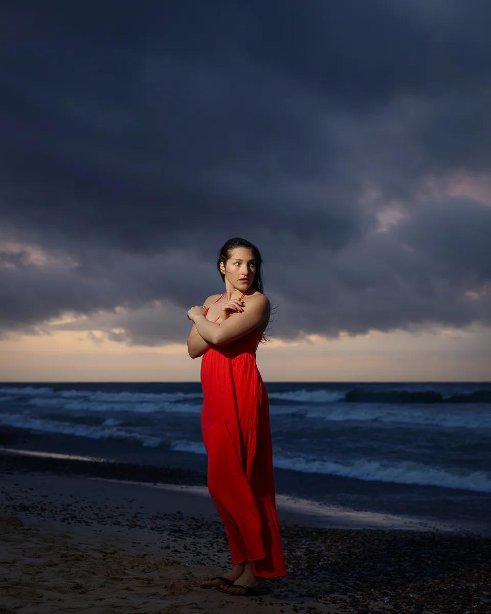 Woman in red dress on a stormy beach.