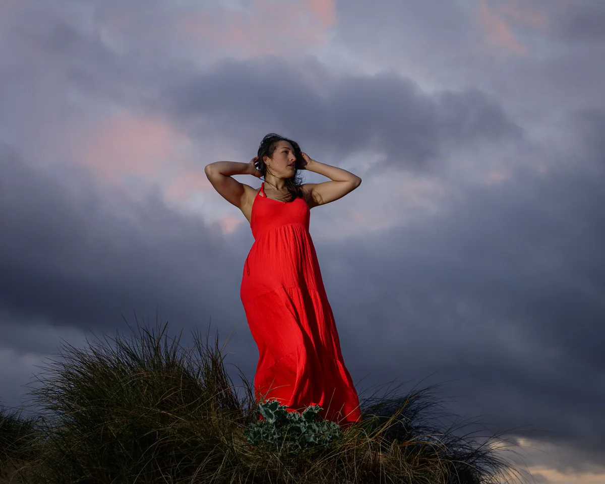 Woman in red dress under cloudy sky