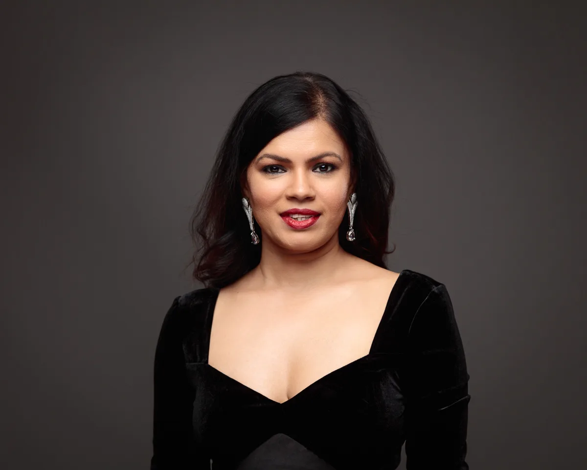Woman in black dress with long earrings, smiling portrait.