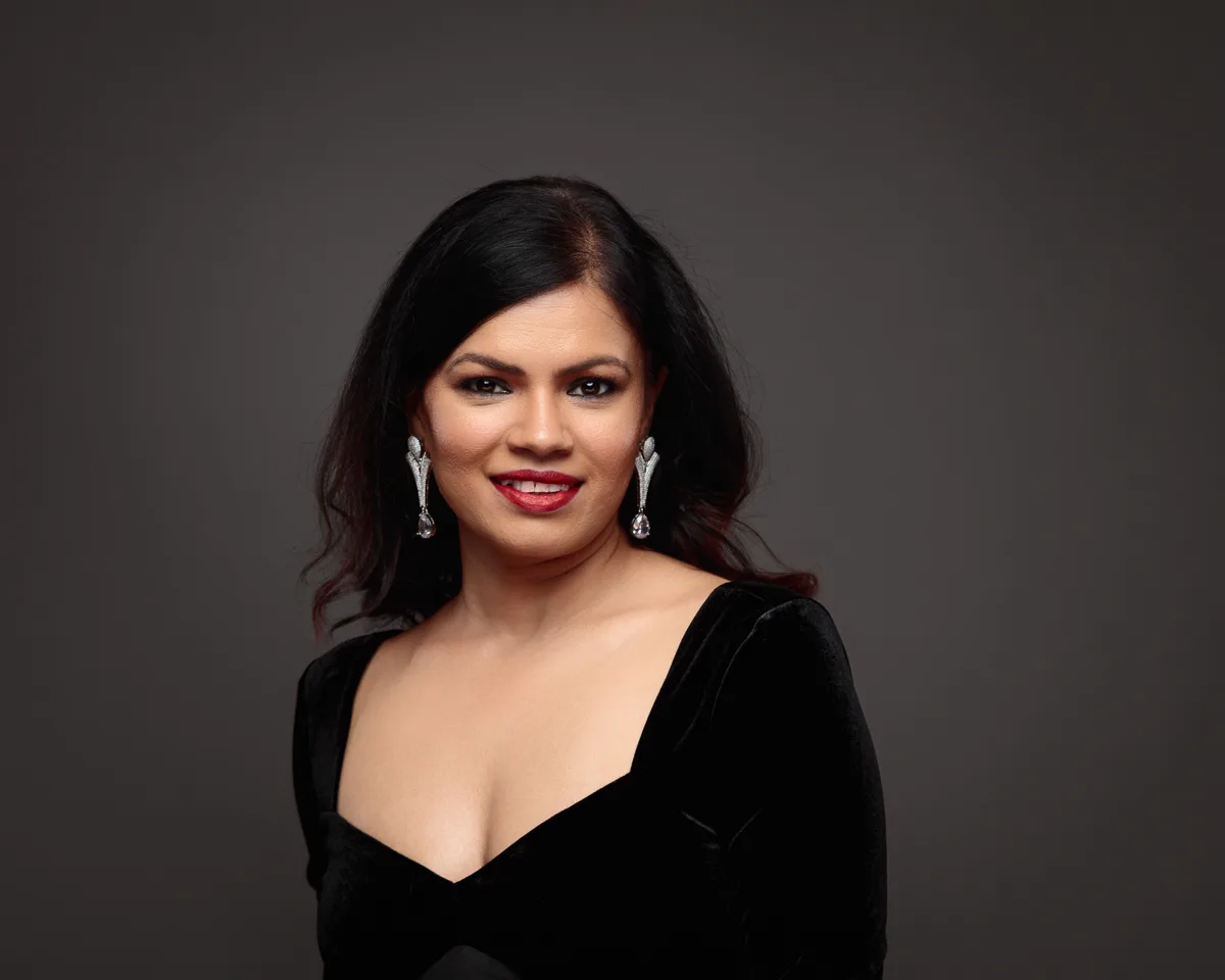 Woman in black dress with silver earrings smiling.