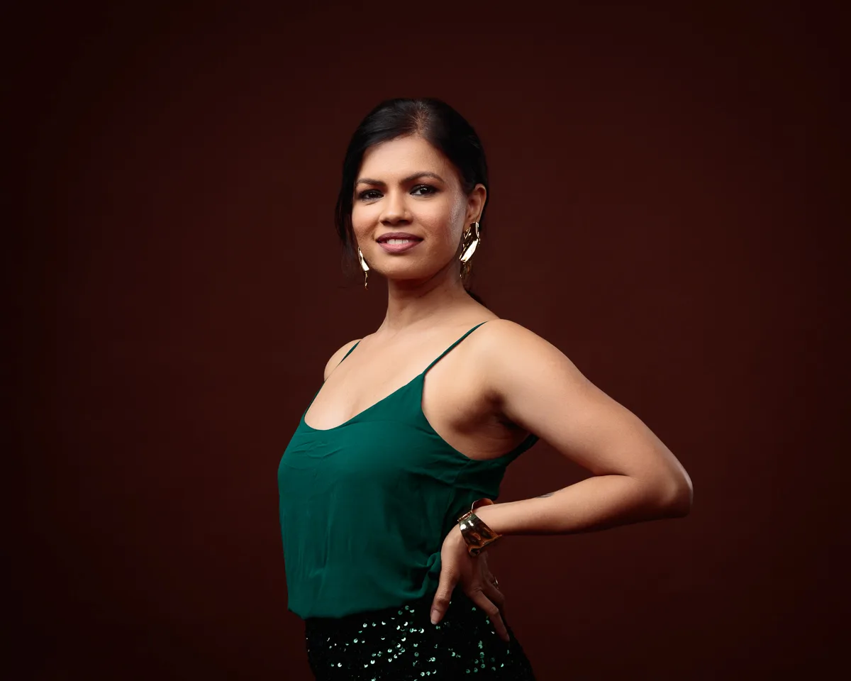 Woman posing against a dark brown backdrop.