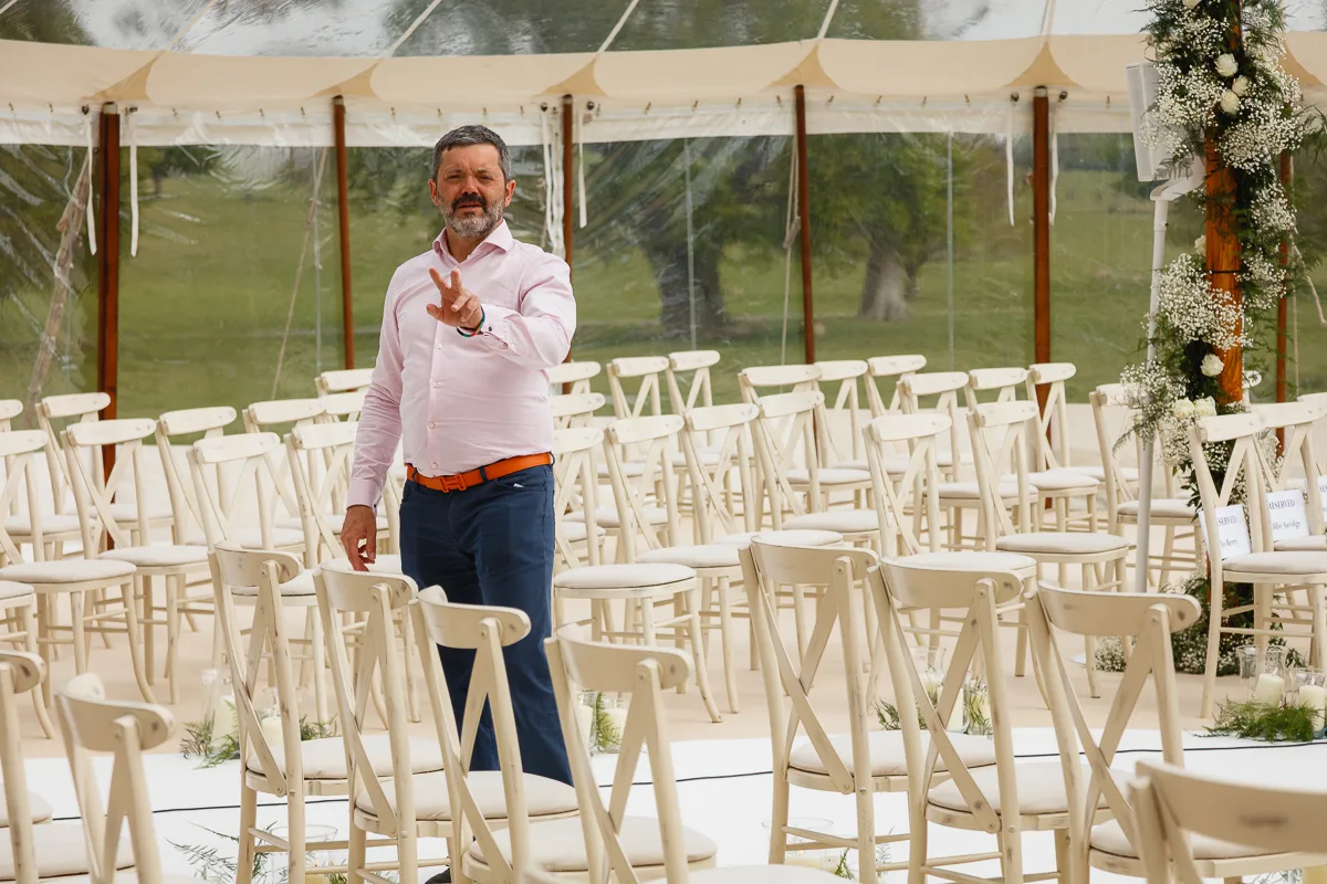 Man arranging chairs in wedding venue tent
