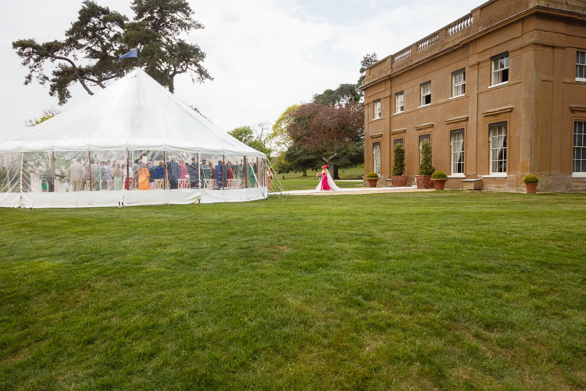 Wedding ceremony in marquee beside historic building.